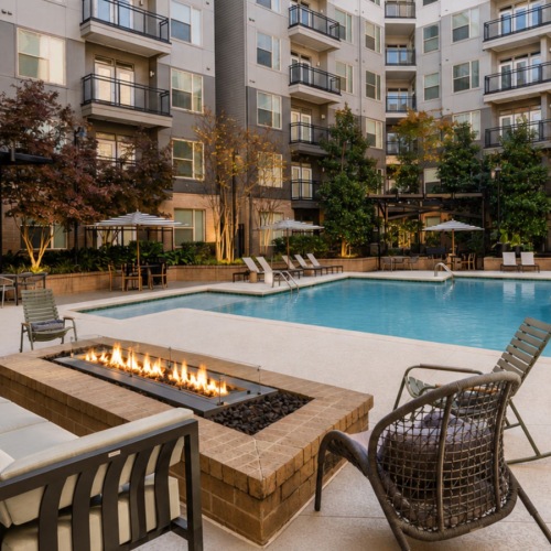 a couch and fire pit in front of a pool