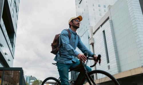 A man with a backpack riding a bicycle in the city.